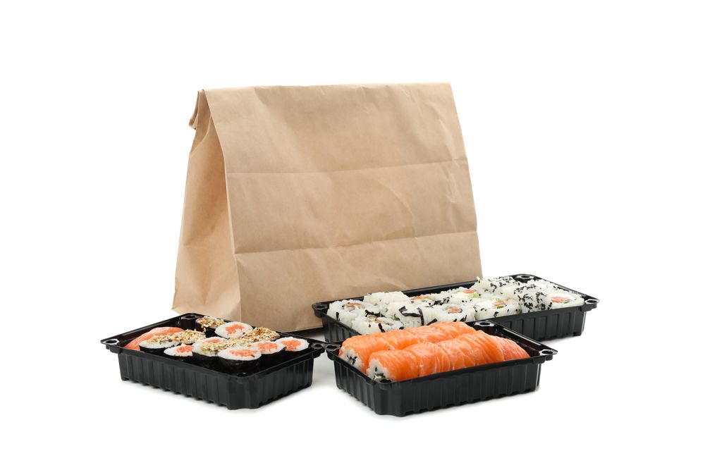 Containers with sushi isolated on plain background. Food delivery