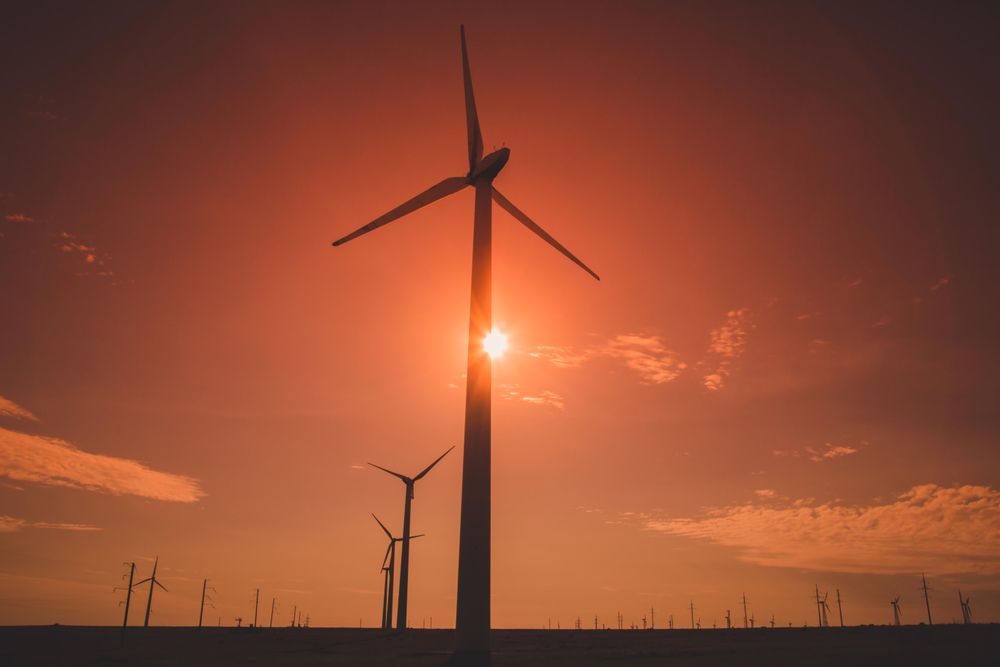Wind turbine under orange sky during sunset