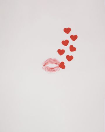 Kiss with small red hearts coming out of it on a plain background
