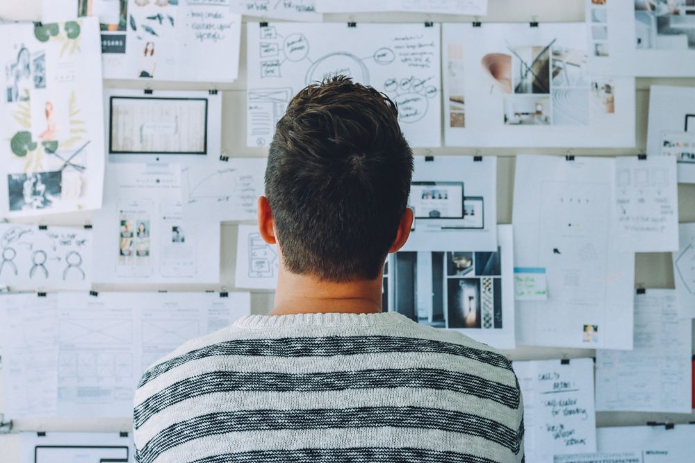Back view of man standing against notes of a board