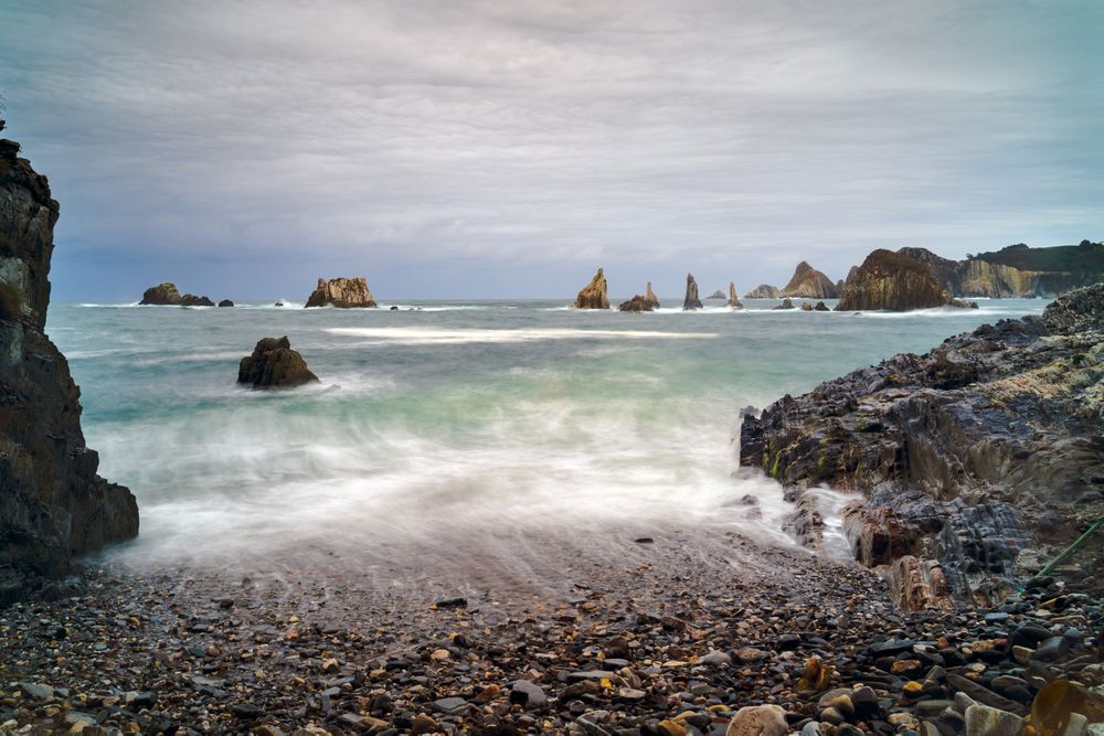 Rocky peaks protrude from water in cloudy day