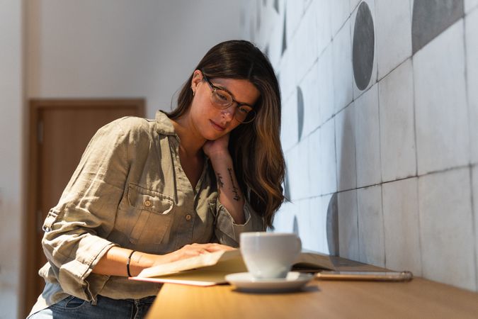 Dreamy woman with book and coffee in cafe