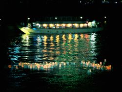 Lit lanterns floating on water near boat at night 5pDBg5