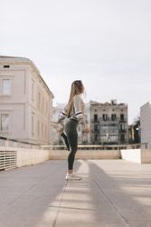 Side view of woman standing and stretching her leg on a city roof top