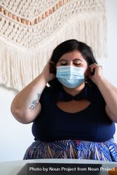 Woman adjusting her face mask in a bright modern office 4ZJlA4