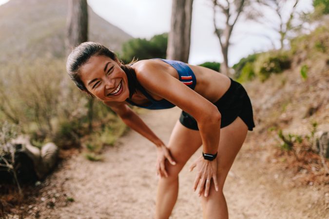Female runner in sportswear taking a break after running workout and laughing
