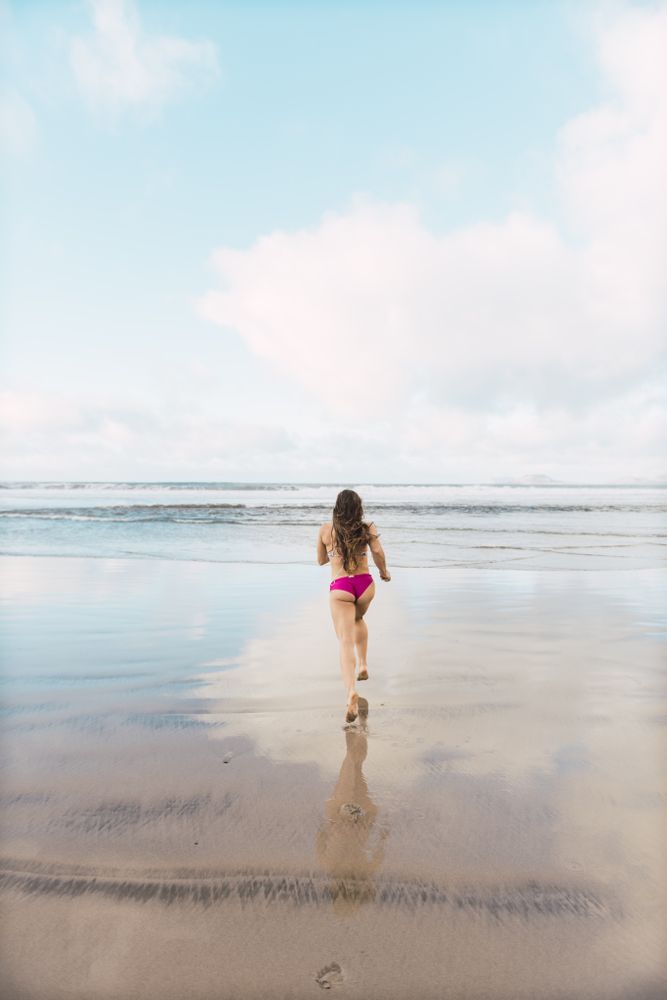 Woman in swimwear running near sea
