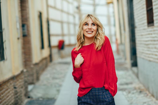 Smiling blond woman in red sweater walking down the street