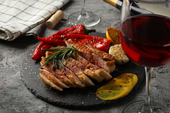 Chopped fried pork steak, vegetables and wine on gray background. Grilled food