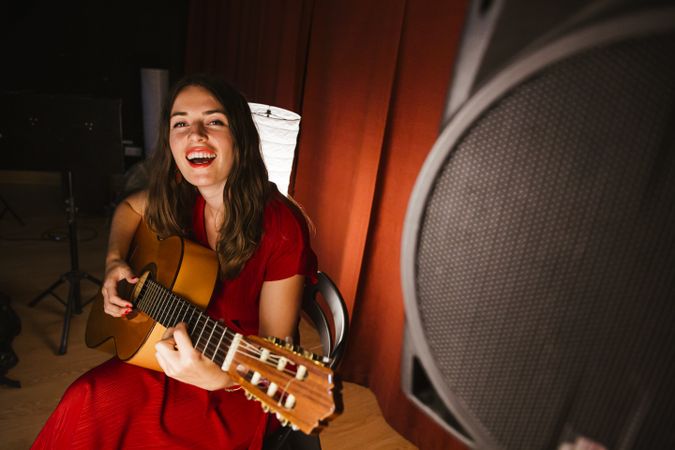 Creative woman singing and playing guitar on stage