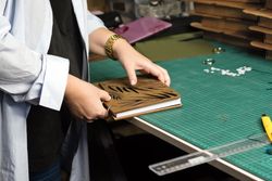 Female hands hold notebook with removable blocks and wooden cover together in workshop
