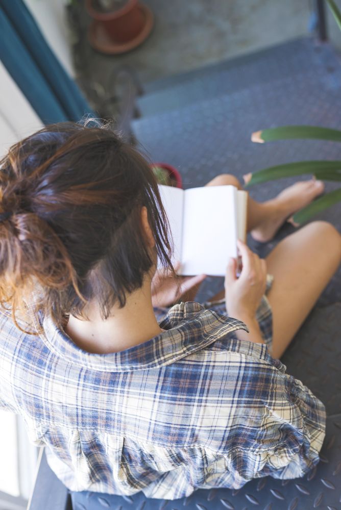 Looking over shoulder of woman reading book on stairs