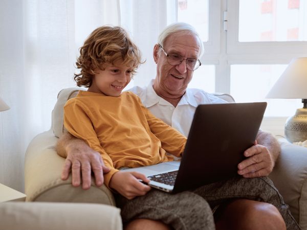 Cheerful grandson with grandfather browsing netbook