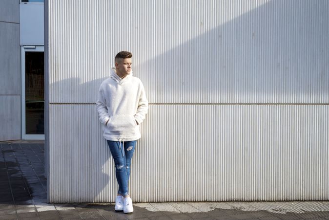 Portrait of young man with hands in pocket standing in front of wall outside