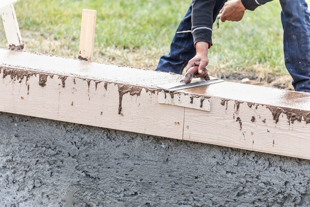 Construction Worker Using Trowel On Wet Cement Forming Coping Around New Pool