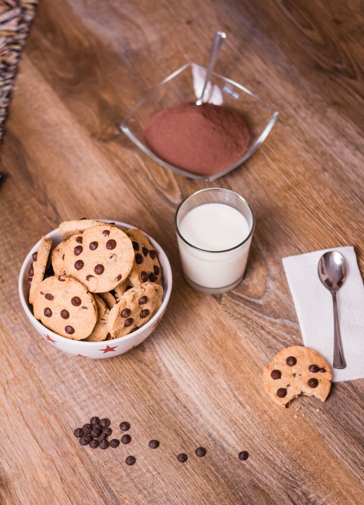 Chocolate chip cookies and milk on wood background