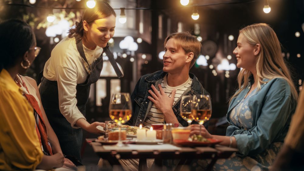Young Men and Women Having Fun Conversations on a Terrace, Enjoying Tasty Food and Beverages
