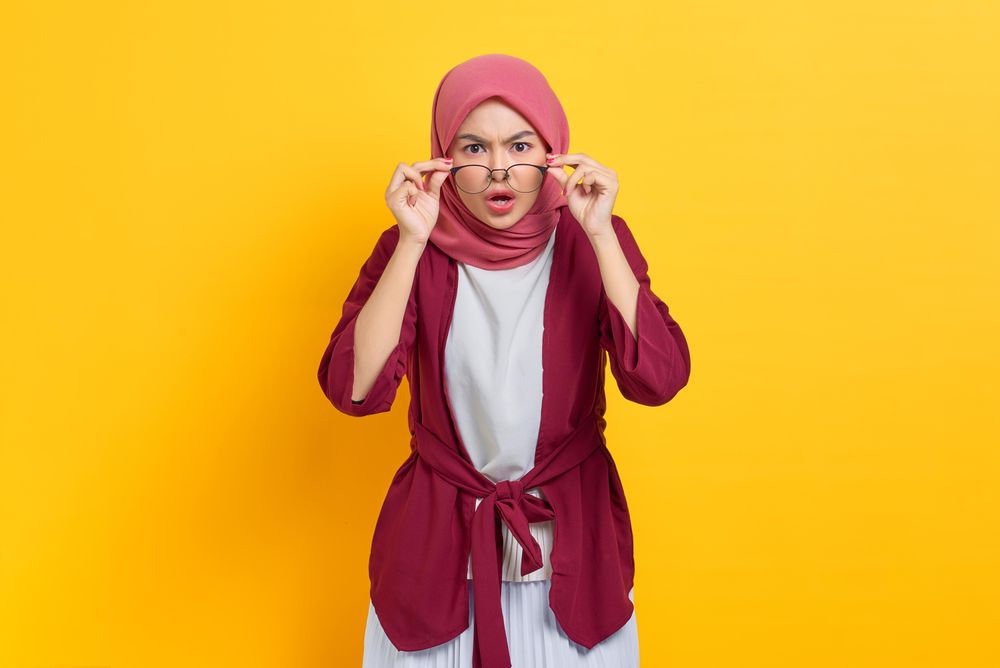 Stern woman in red headscarf and glasses looking at camera