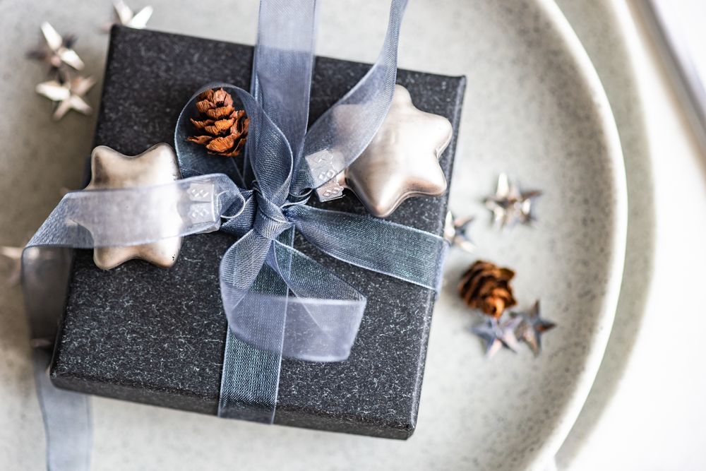 Top view of festive Christmas card concept with blue gift box on grey background with copy space