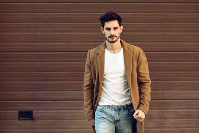 Male with beard in smart winter jacket in front of brown wall