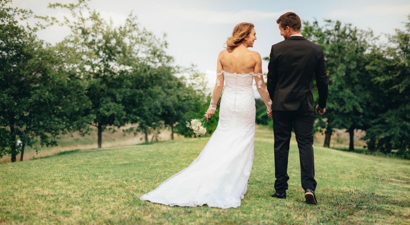 Couple holding hands and walking outdoors on wedding day