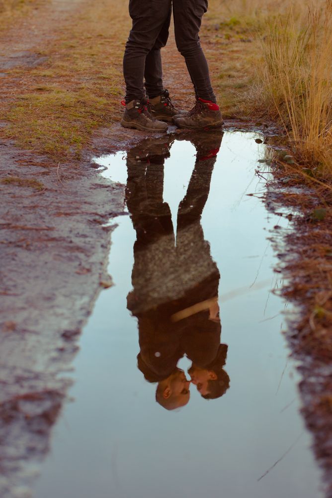 Men hugging and kissing near water puddle