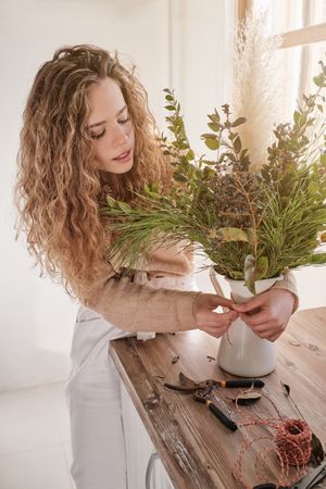 Young woman decorating bouquet in vase
