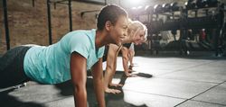 Woman smiling while planking in gym class