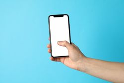 Female hand holding phone with empty screen on blue background