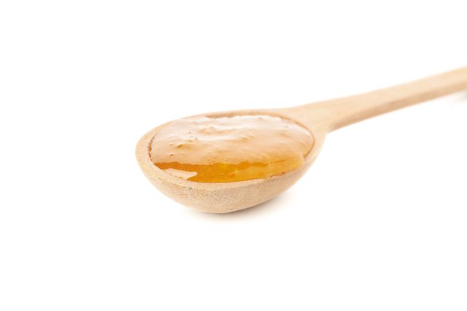 Spoon with orange jam isolated on plain background
