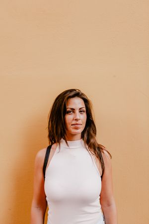 Young brunette standing against orange background