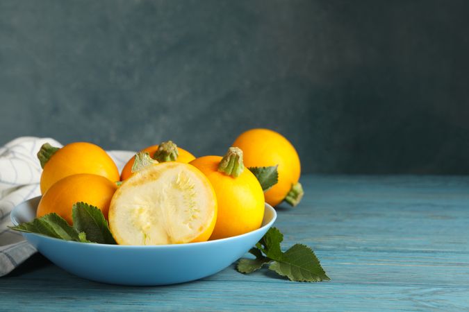Bowl with round zucchini and napkin on wooden table