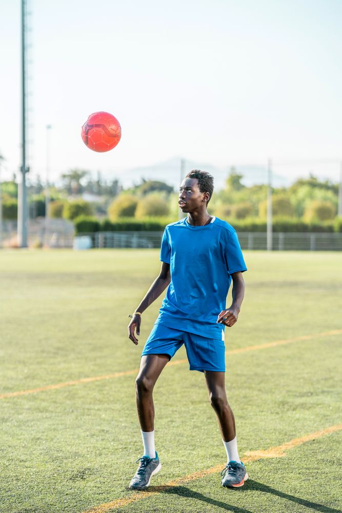 Black teenager juggling football ball