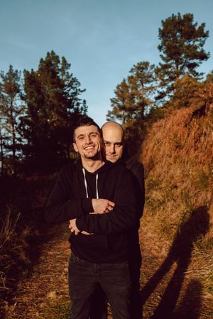 Smiling men hugging on path in park