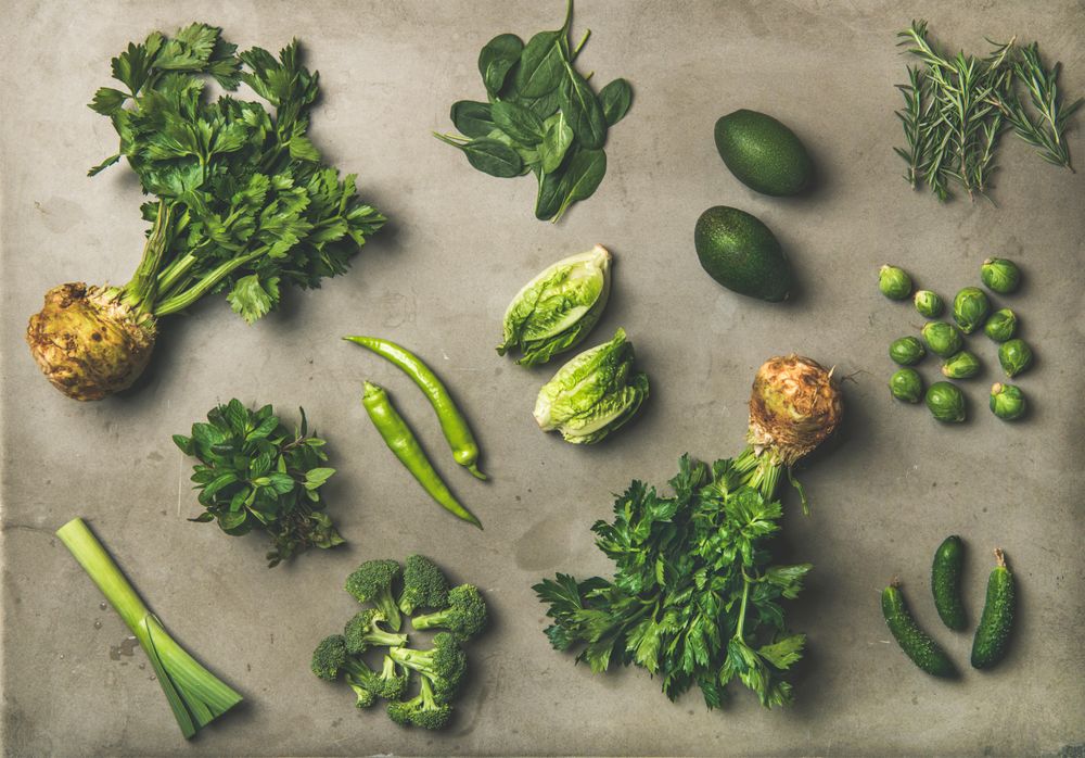 Arrangement of fresh green garden vegetables on concrete surface