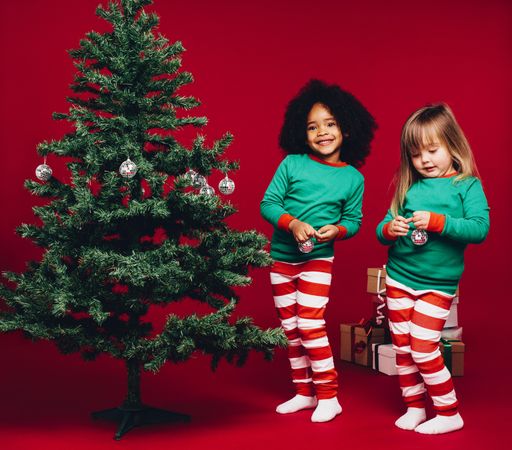 Two little girls standing beside a christmas tree