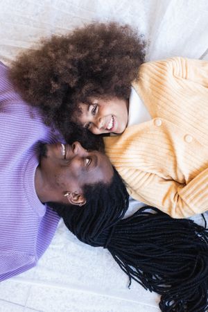 Happy Black girl lying with father on bed
