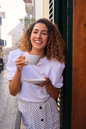 Smiling woman drinking coffee and looking at camera