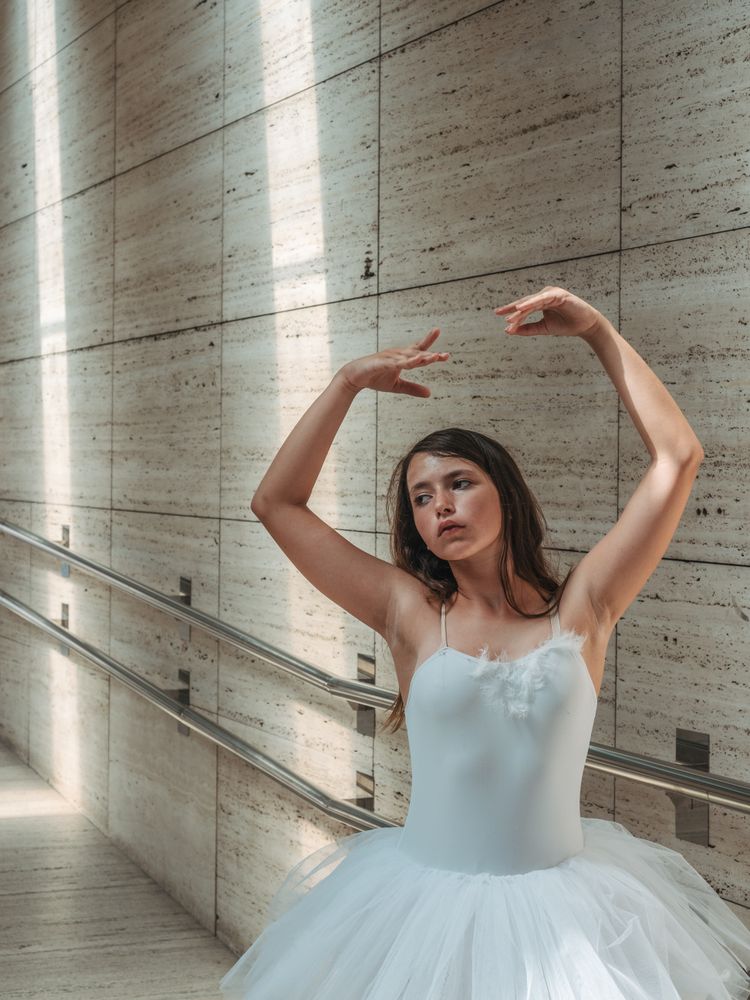 Ballerina doing ballet posing at rail in classroom