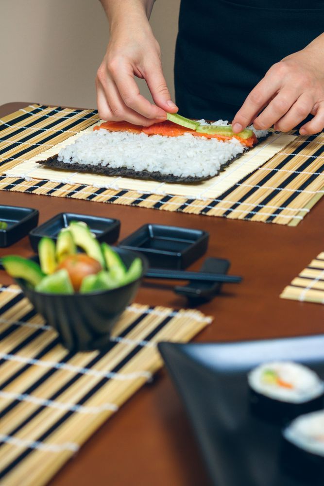 Chef placing avocado filling on rice for sushi rolls