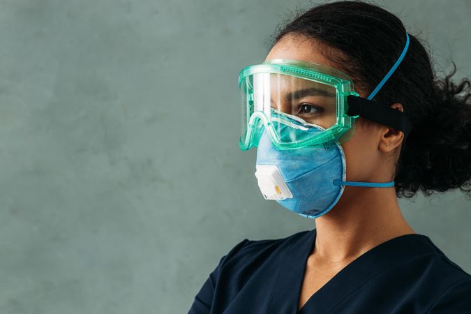 Side view of Black female medical professional in facemask and eye goggles