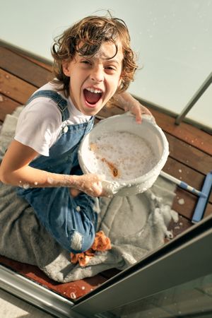 Excited boy with basin sitting on floor