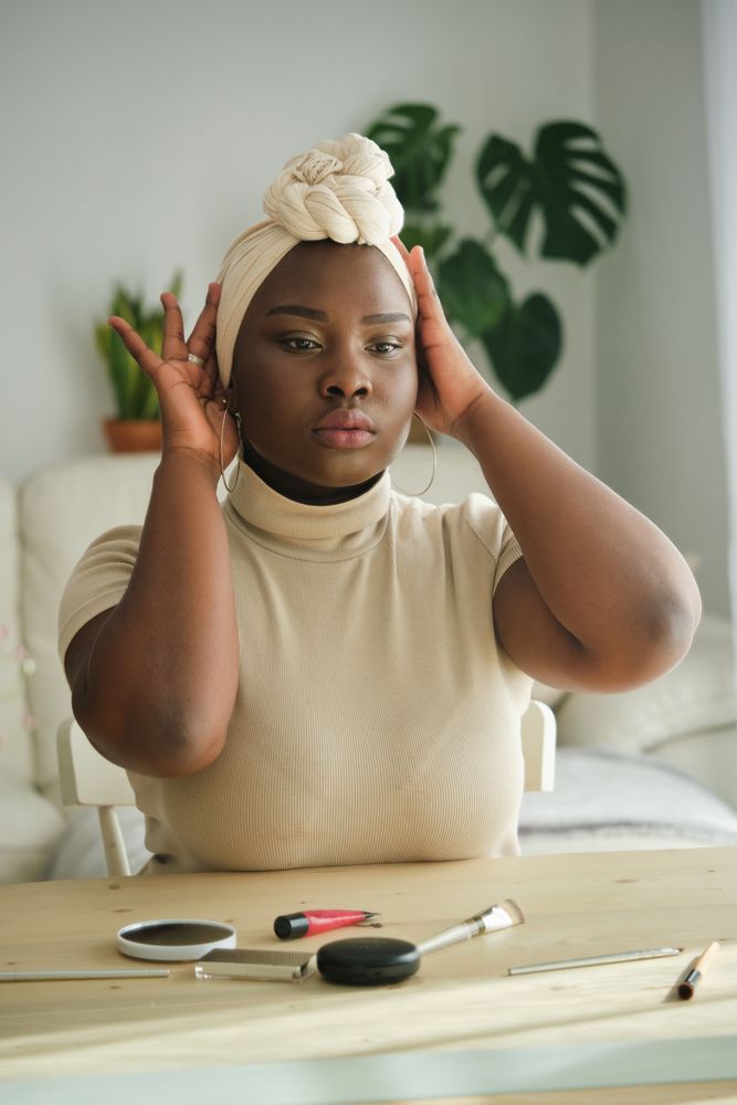 Black lady adjusting headscarf in front of mirror