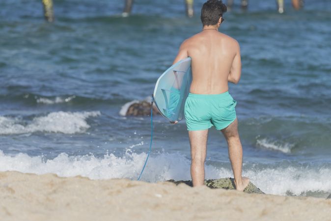 Male surfer with blue board approaching the shore