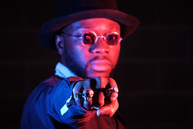 Stylish Black guy in sunglasses showing fist in studio