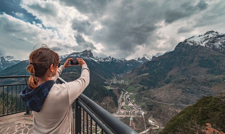 Traveler taking pictures of mountains from pier