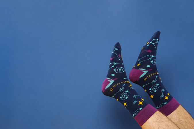 Male legs in socks on blue background, space for text