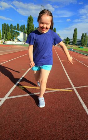 Young child running across finish line on running track