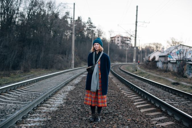 Woman in skirt and navy jacket in between train tracks