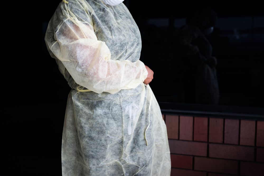 Close up cropped shot of nurse tying the side of disposable gown